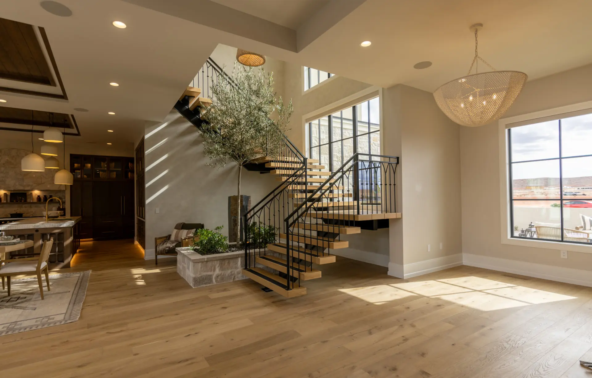 Entry with a woven dome chandelier beside a floating stair and olive tree