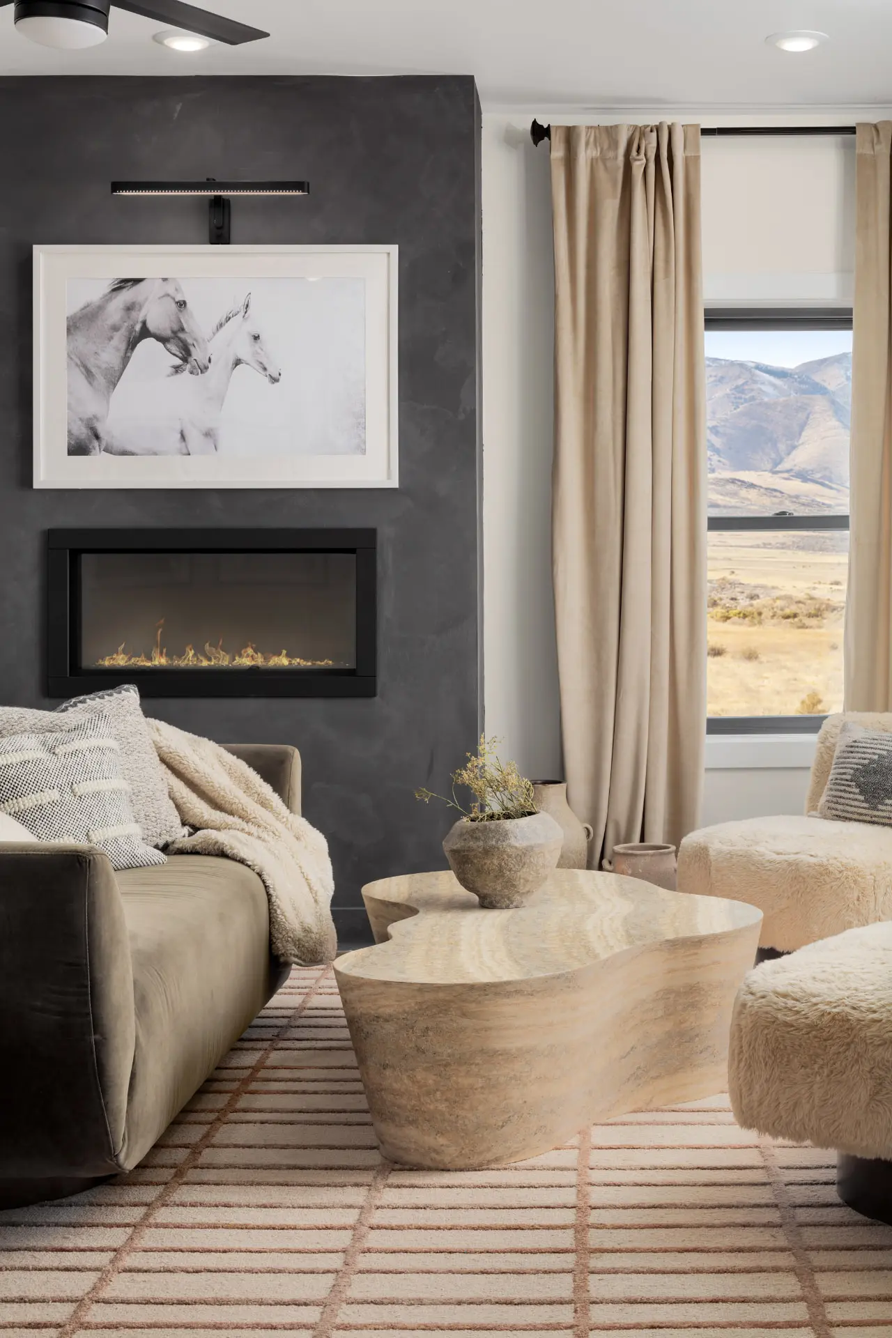 Primary sitting area with a linear fireplace and blackened picture light above framed art