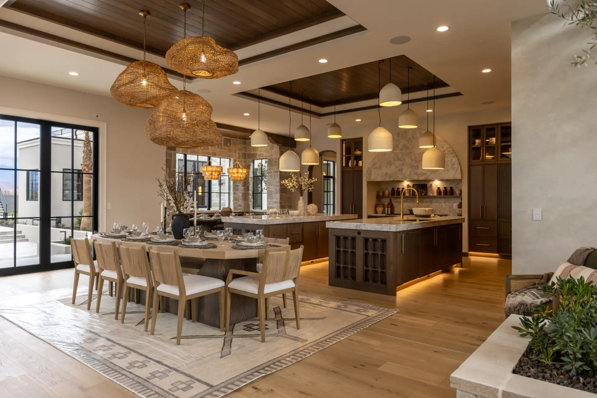 Woven pendants over a long dining table with bell pendants across the kitchen island