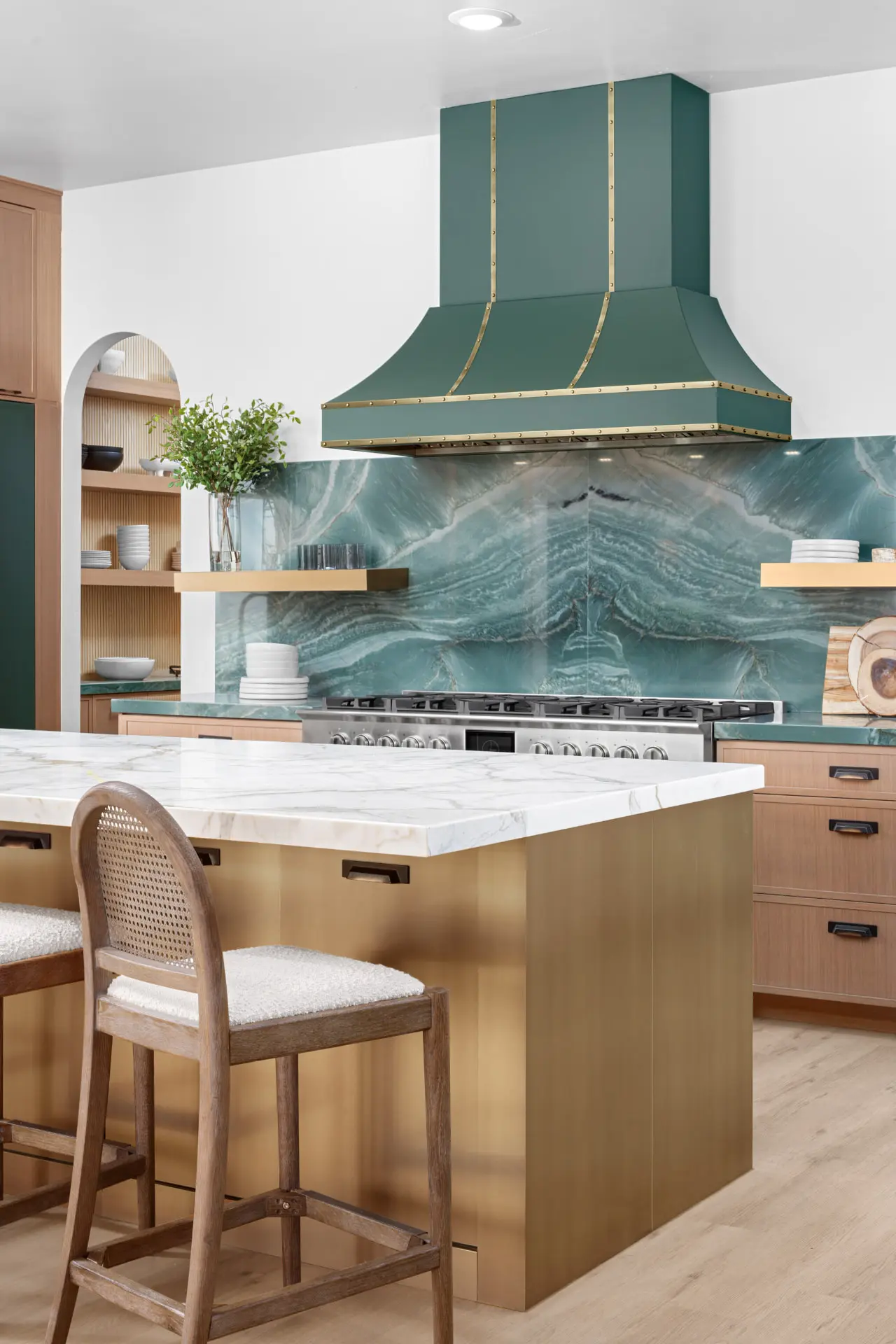 Kitchen with a green range hood, quartzite backsplash, and brass island