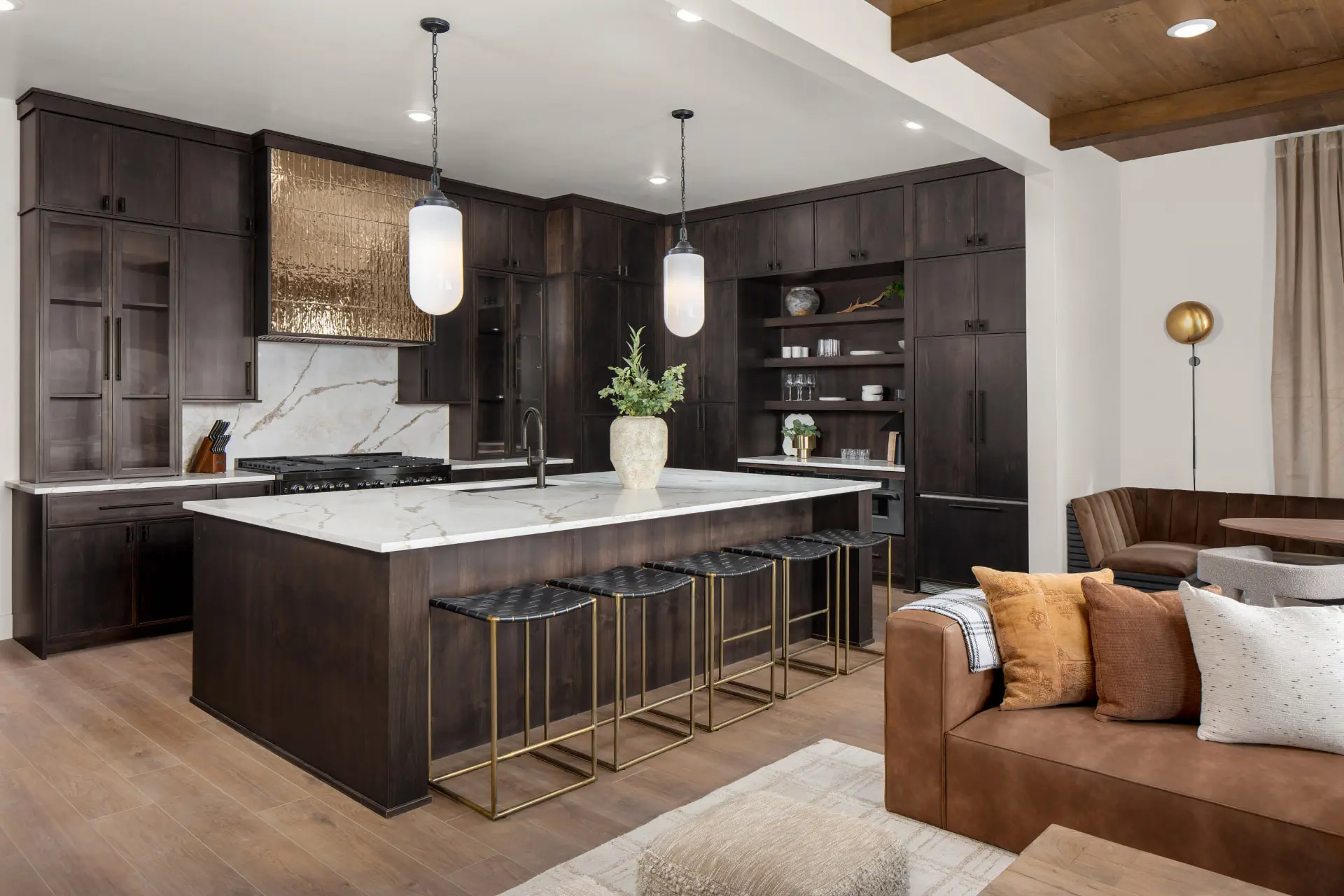 Kitchen island in marble with two frosted glass pendants and a brass tile range hood