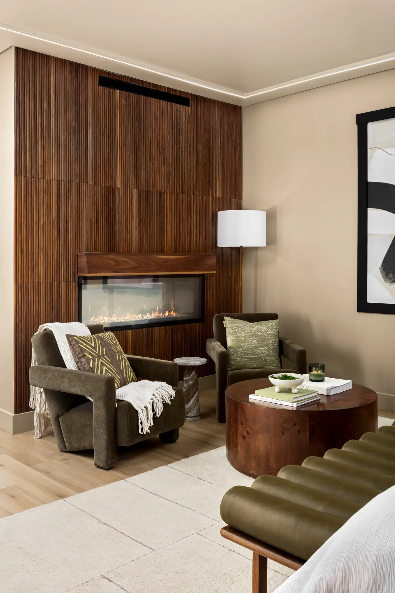 Primary suite sitting area with a slatted walnut fireplace wall and drum floor lamp