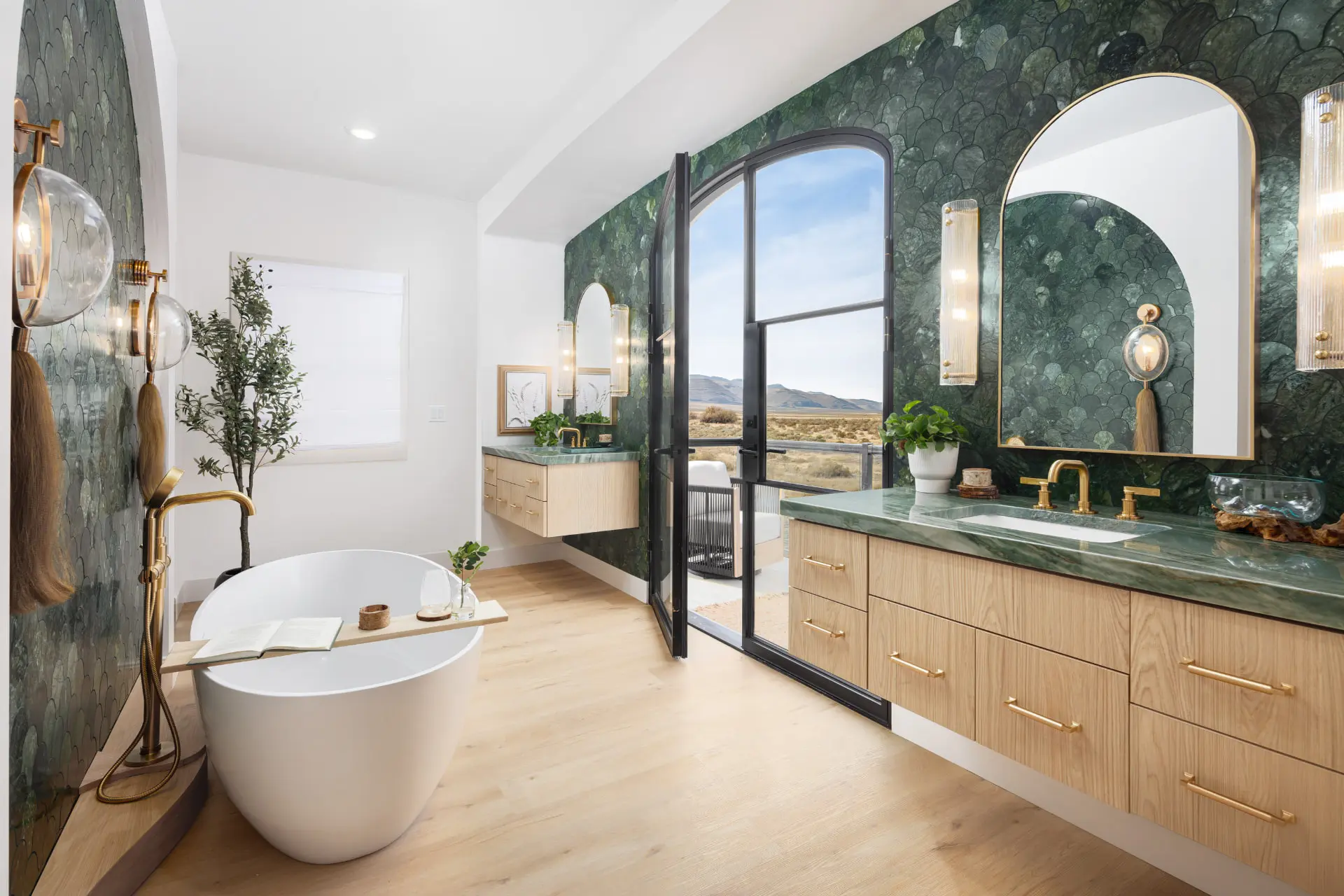 Primary bath with green fish-scale tile, reeded glass sconces, and a freestanding tub