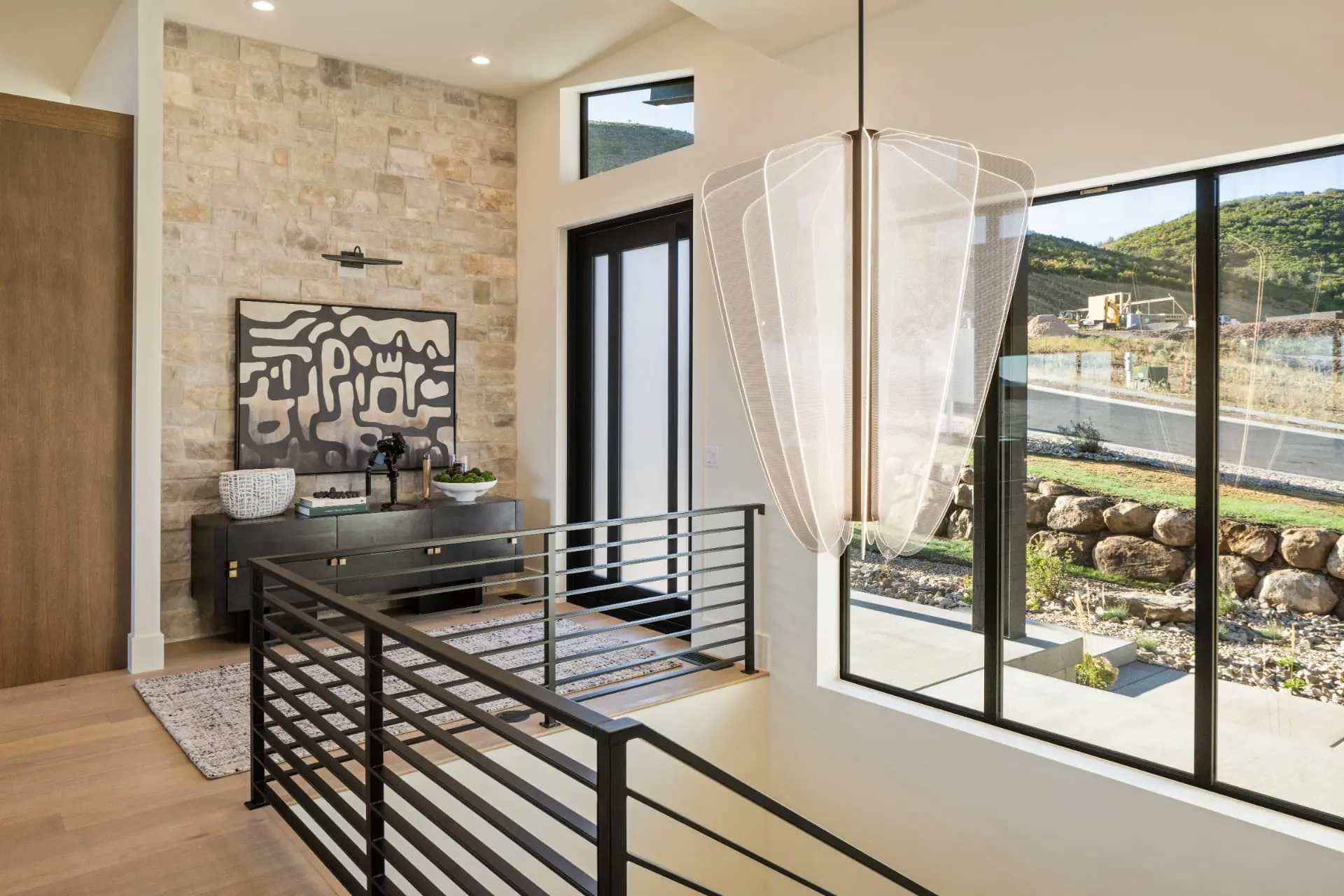 Double-height entry with a sculptural white mesh pendant beside a stone wall