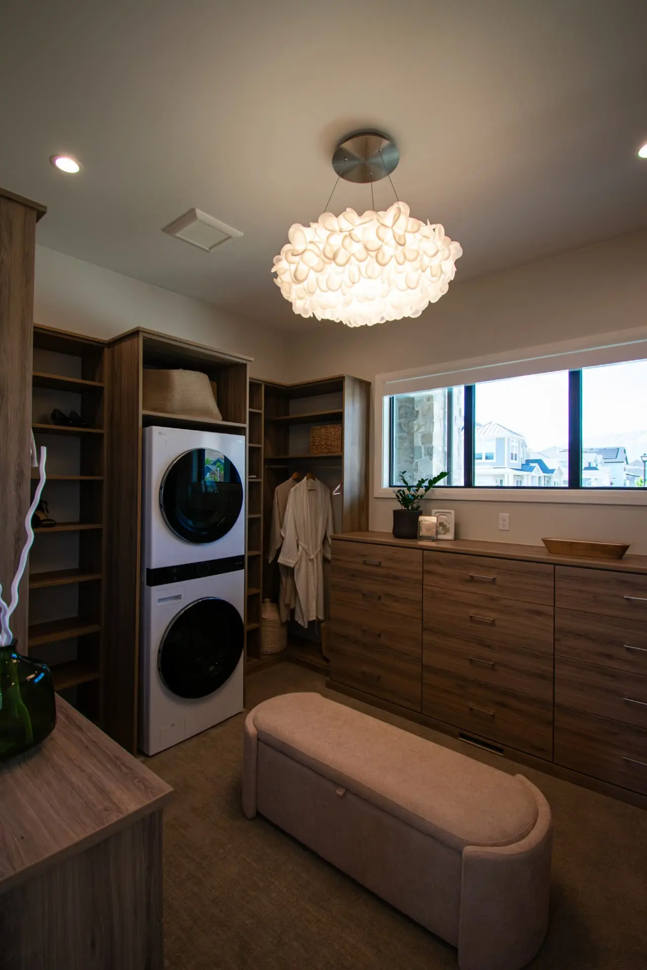 Walk-in primary closet with walnut cabinetry and a petal-shade flush chandelier