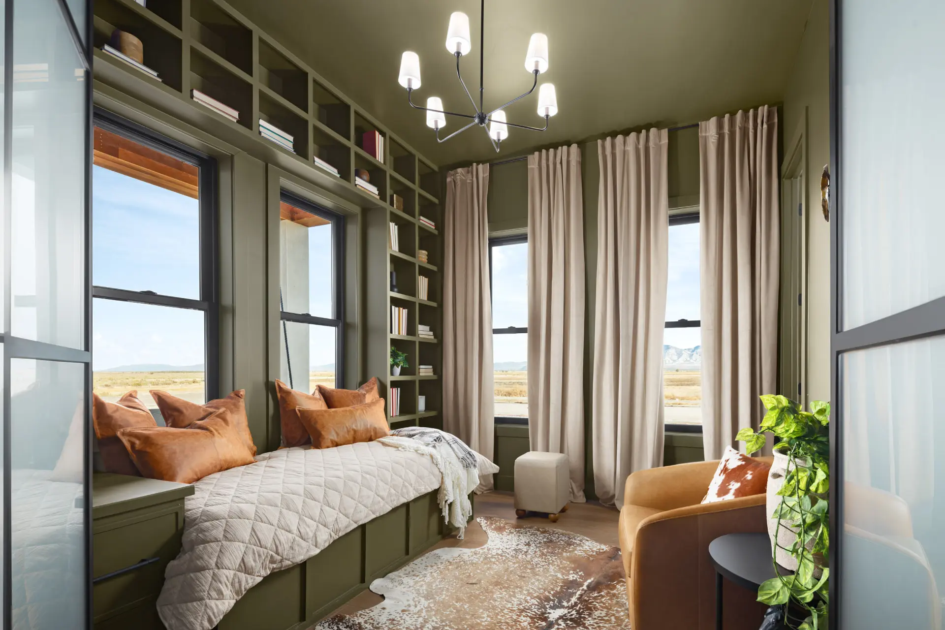 Olive green flex room with built-in bookshelves, a daybed and a six-arm tapered shade chandelier
