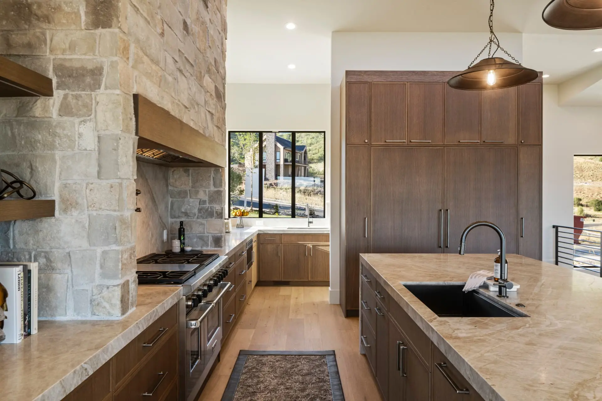 Kitchen with a chain-hung dome pendant over the island and stone range wall