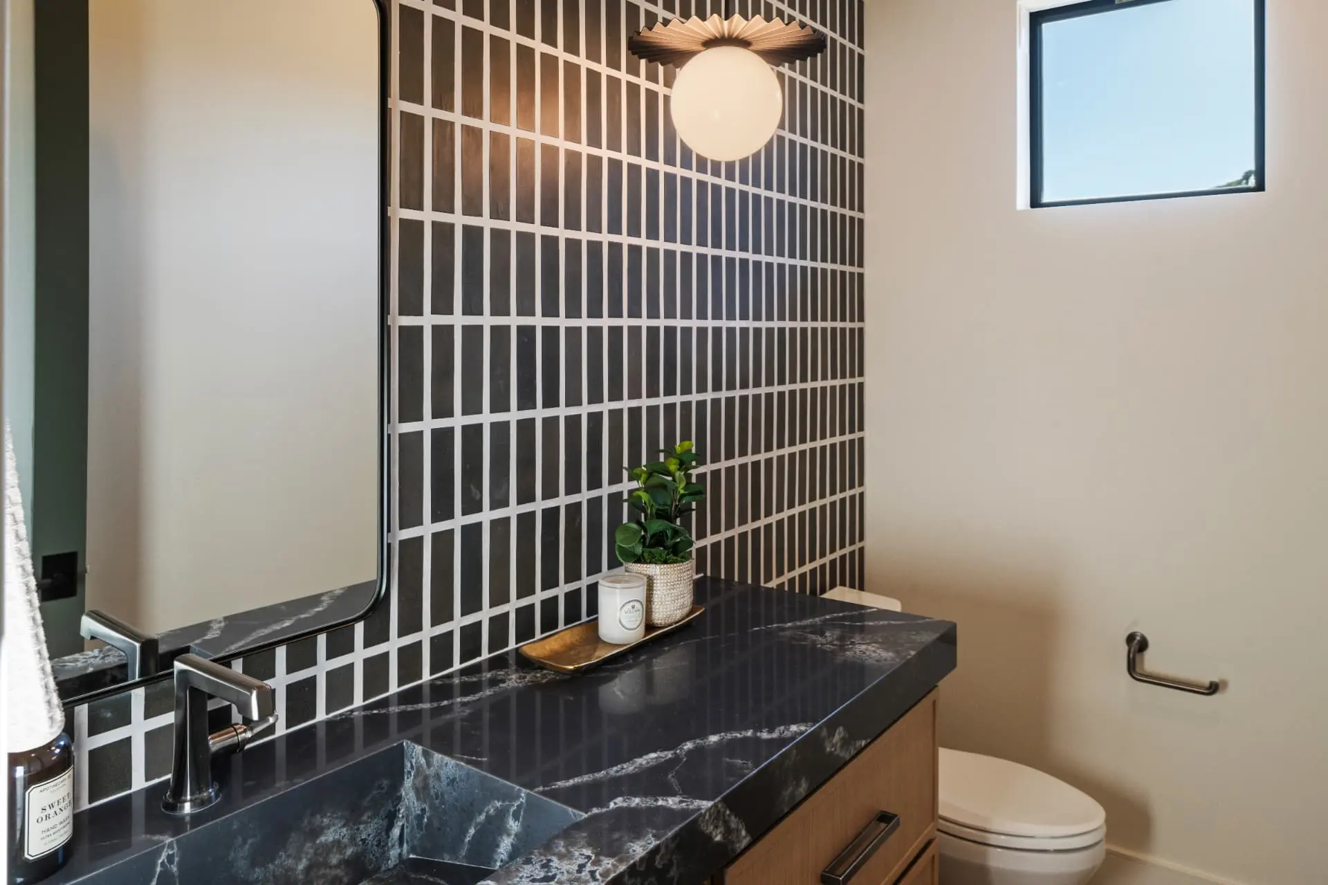 Powder room with a fluted flush mount globe above a tiled accent wall