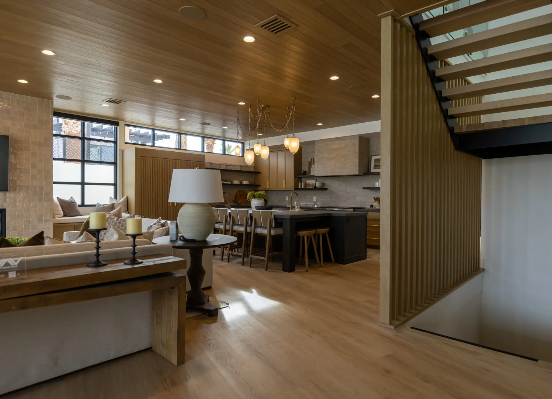 Great room and kitchen under a wood-clad ceiling with an alabaster chain chandelier