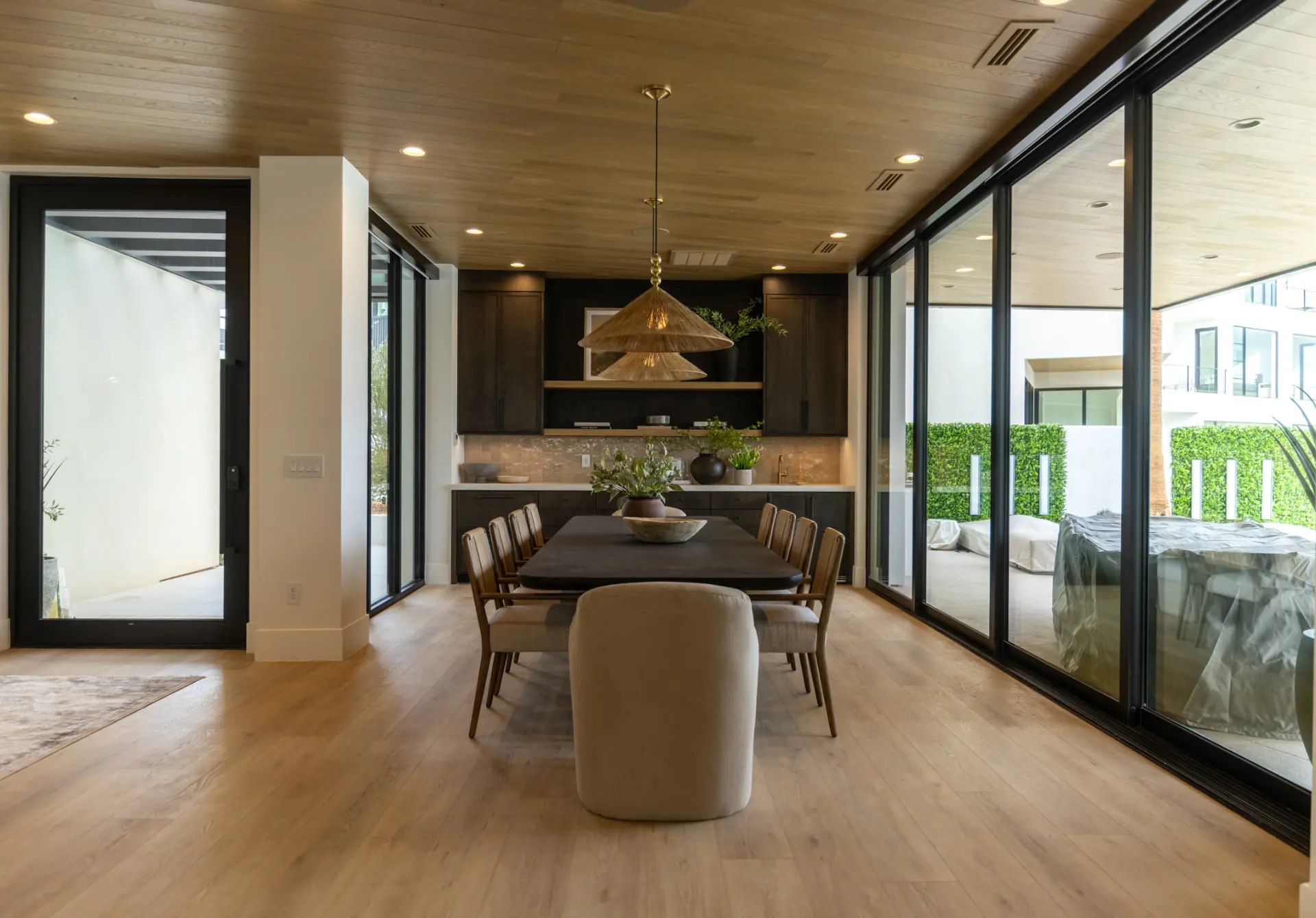 Stacked woven cone pendants centered over a dark dining table
