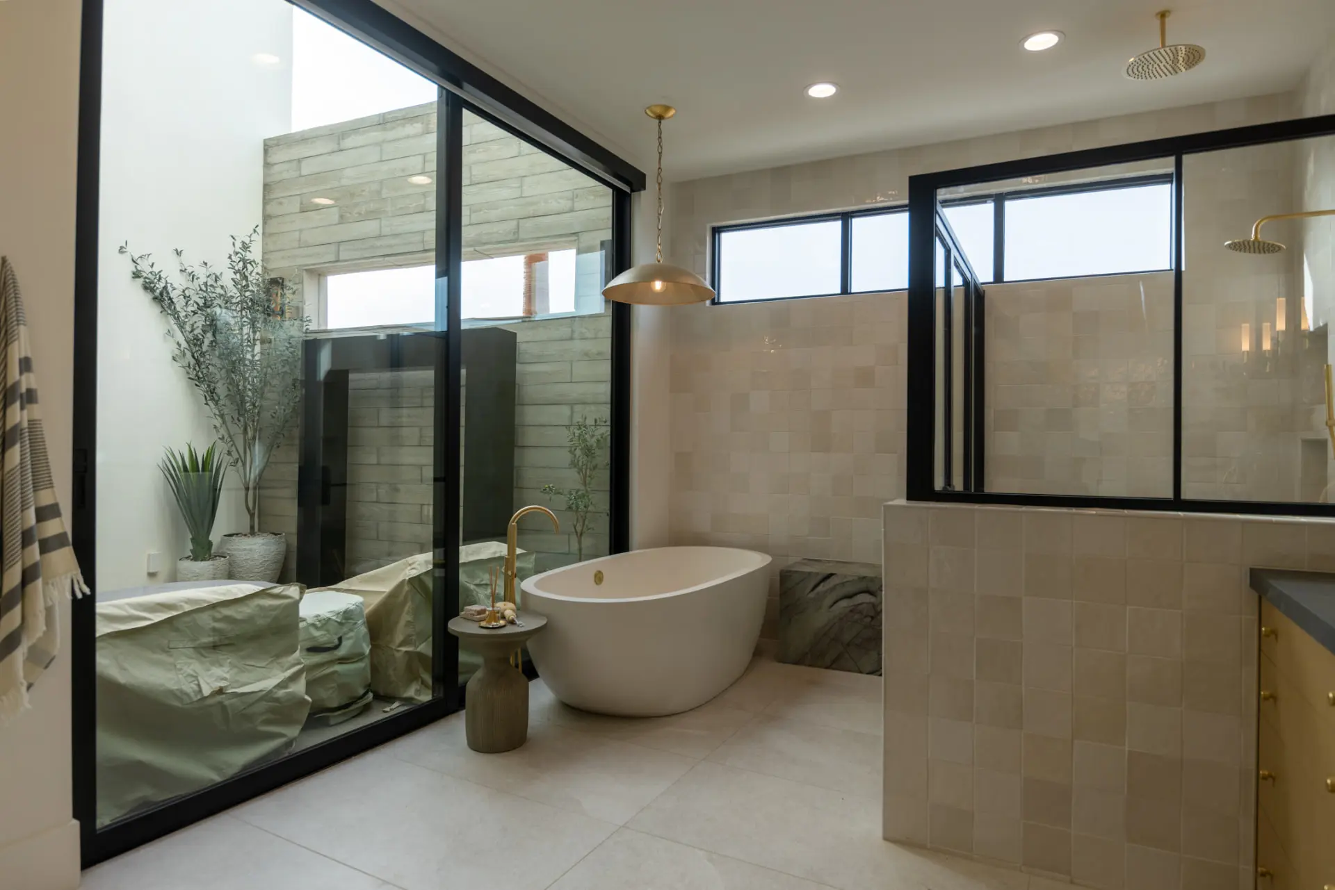 Freestanding tub under a brass dome pendant beside a private courtyard