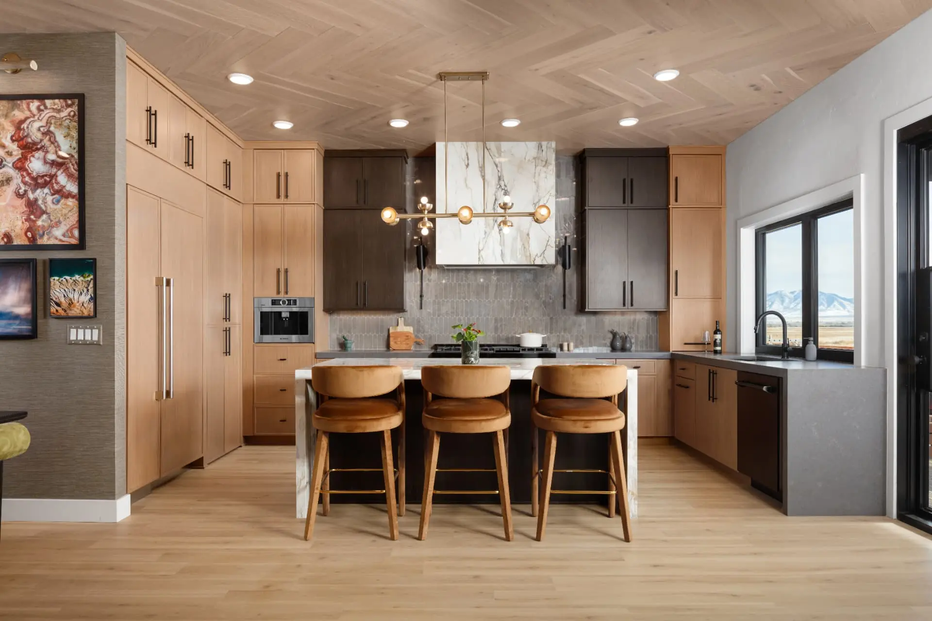 Kitchen with white oak cabinetry, marble hood and a brass linear chandelier above the island