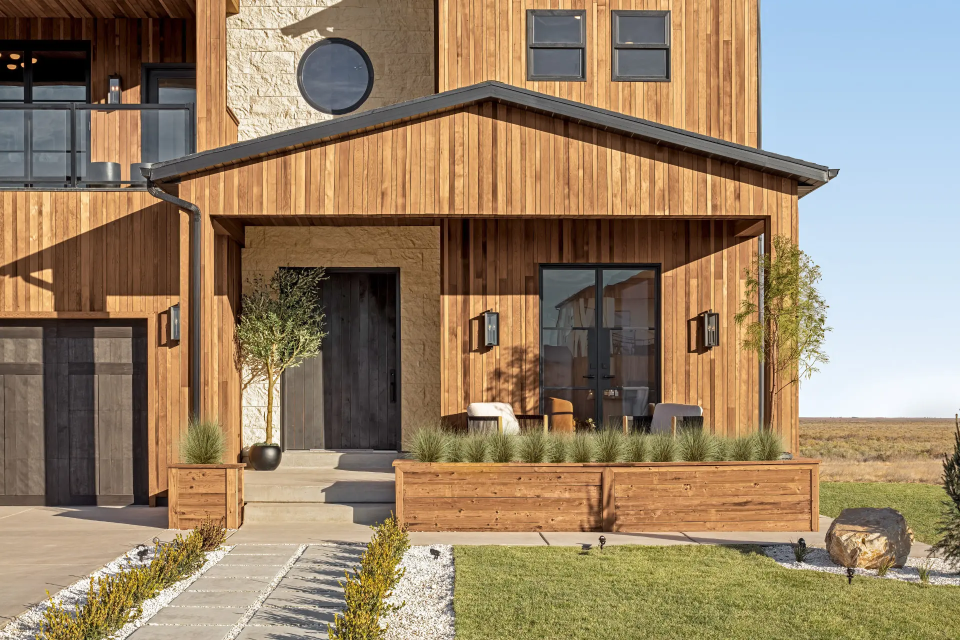 Cedar-clad entry with lantern wall sconces beside a black door