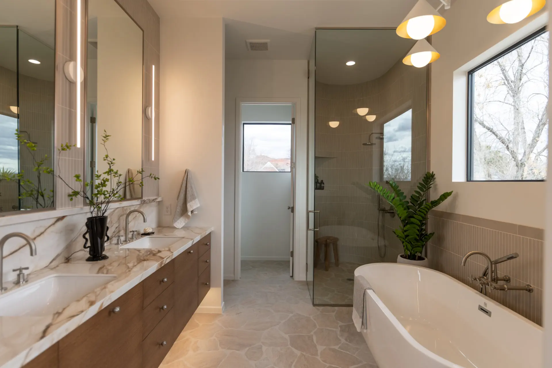 Primary bath with cone pendant fixtures, backlit mirrors, and shower sconces