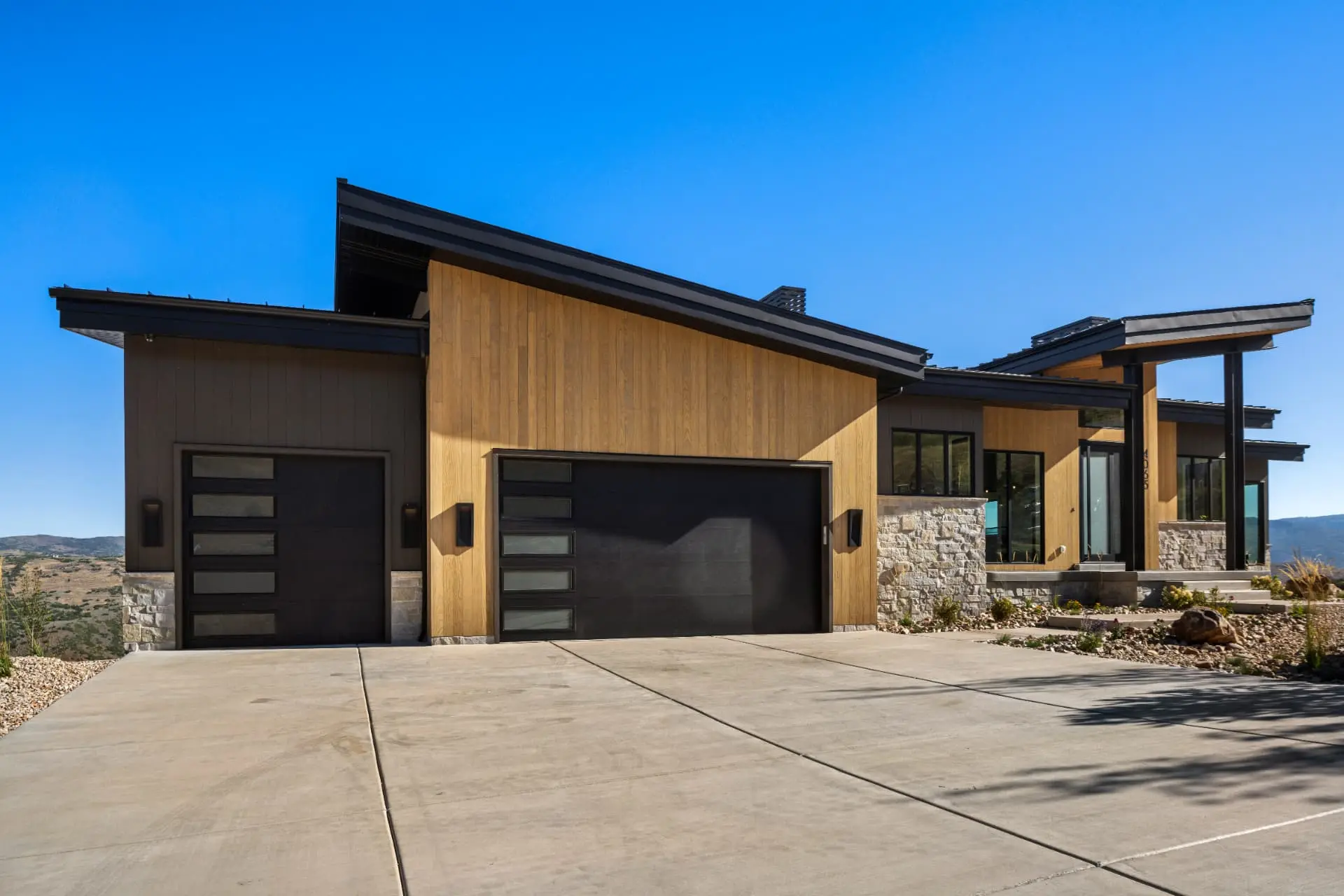 Mountain-modern exterior with wood siding and dark exterior sconces