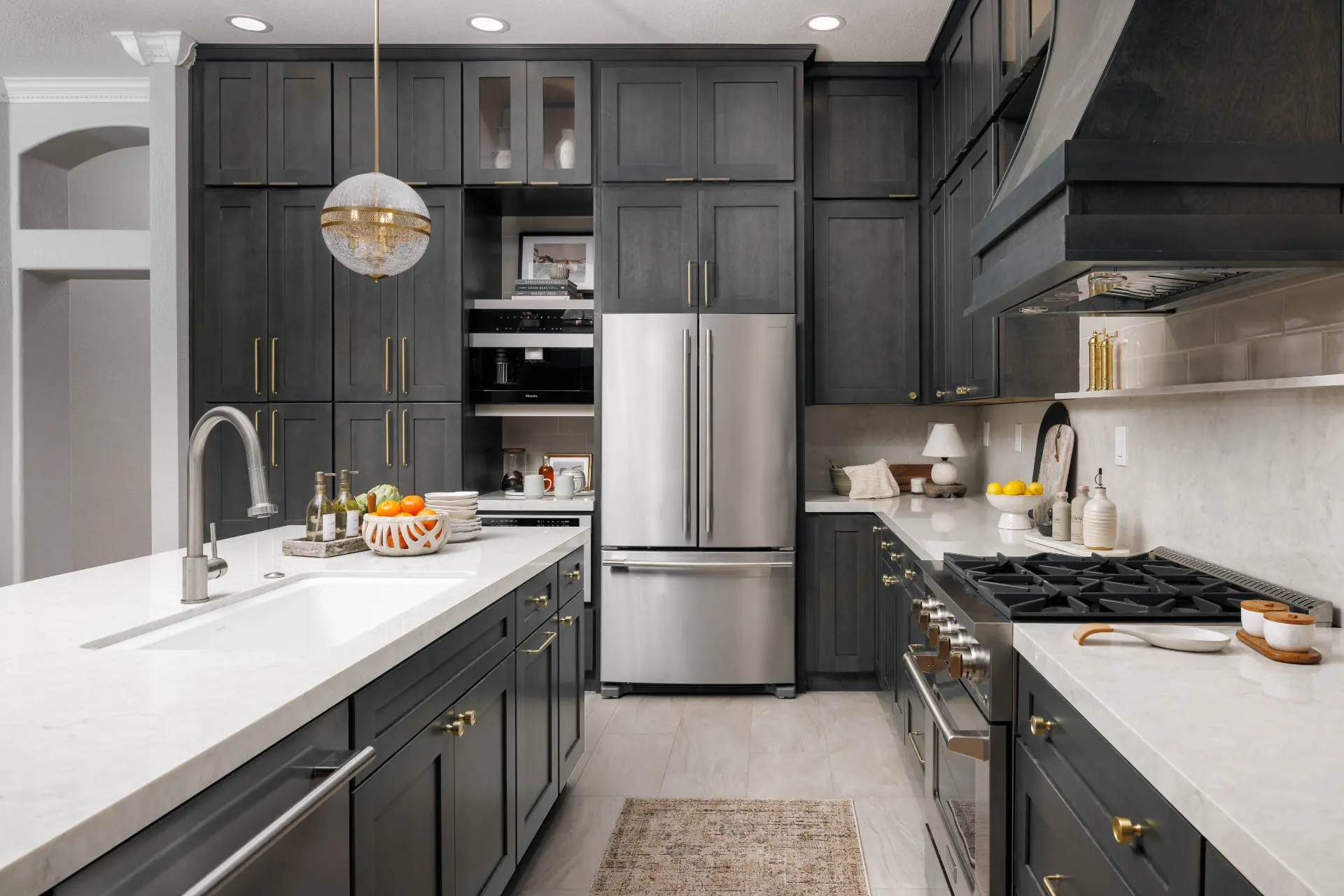 Kitchen view toward the range and hood with a crackled glass globe pendant over the sink