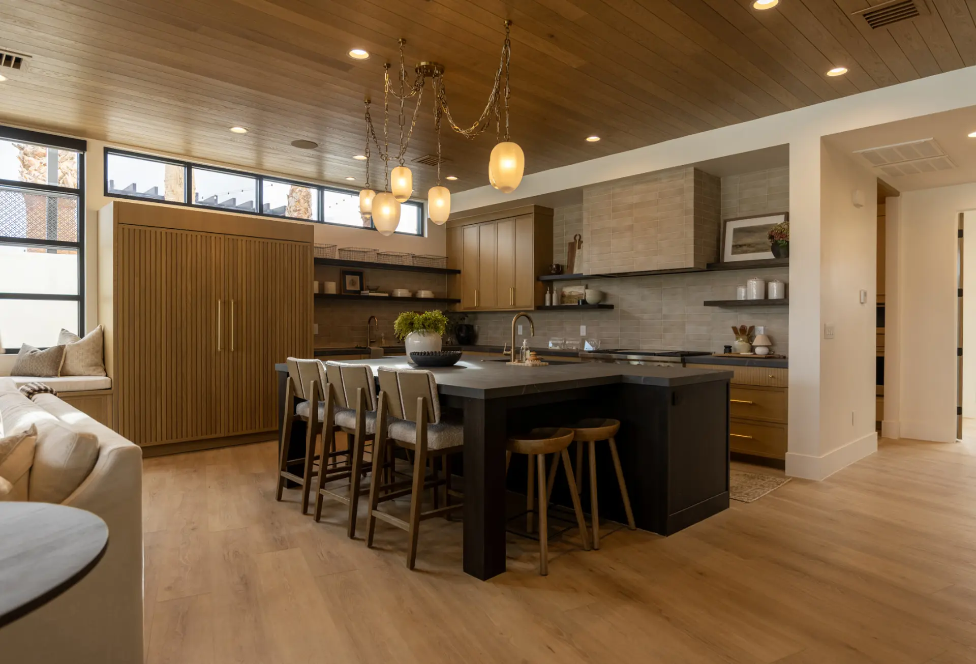 Alabaster chain chandelier above a dark kitchen island with fluted oak cabinetry