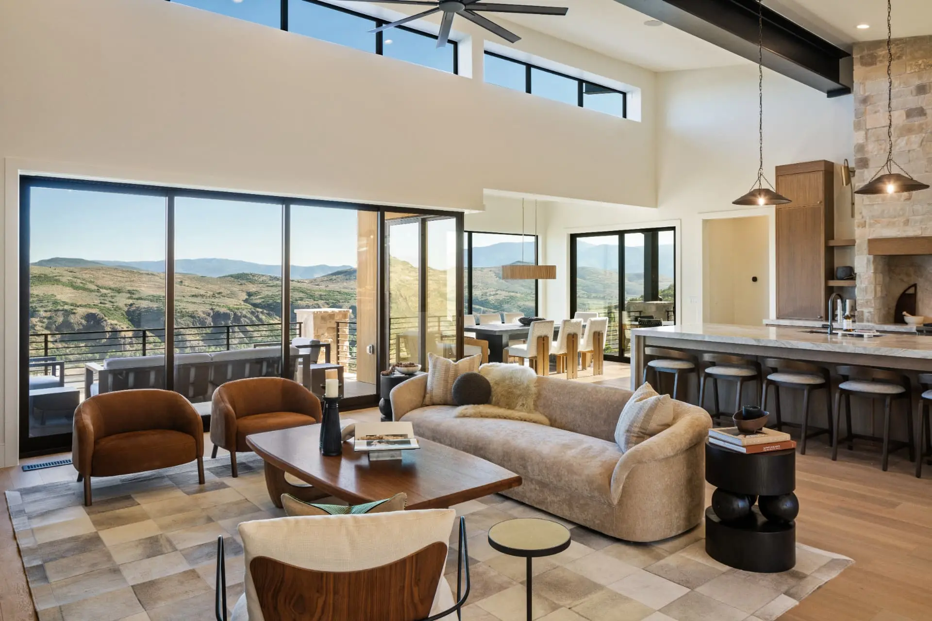 Great room open to the kitchen with chain-hung dome pendants and a large ceiling fan