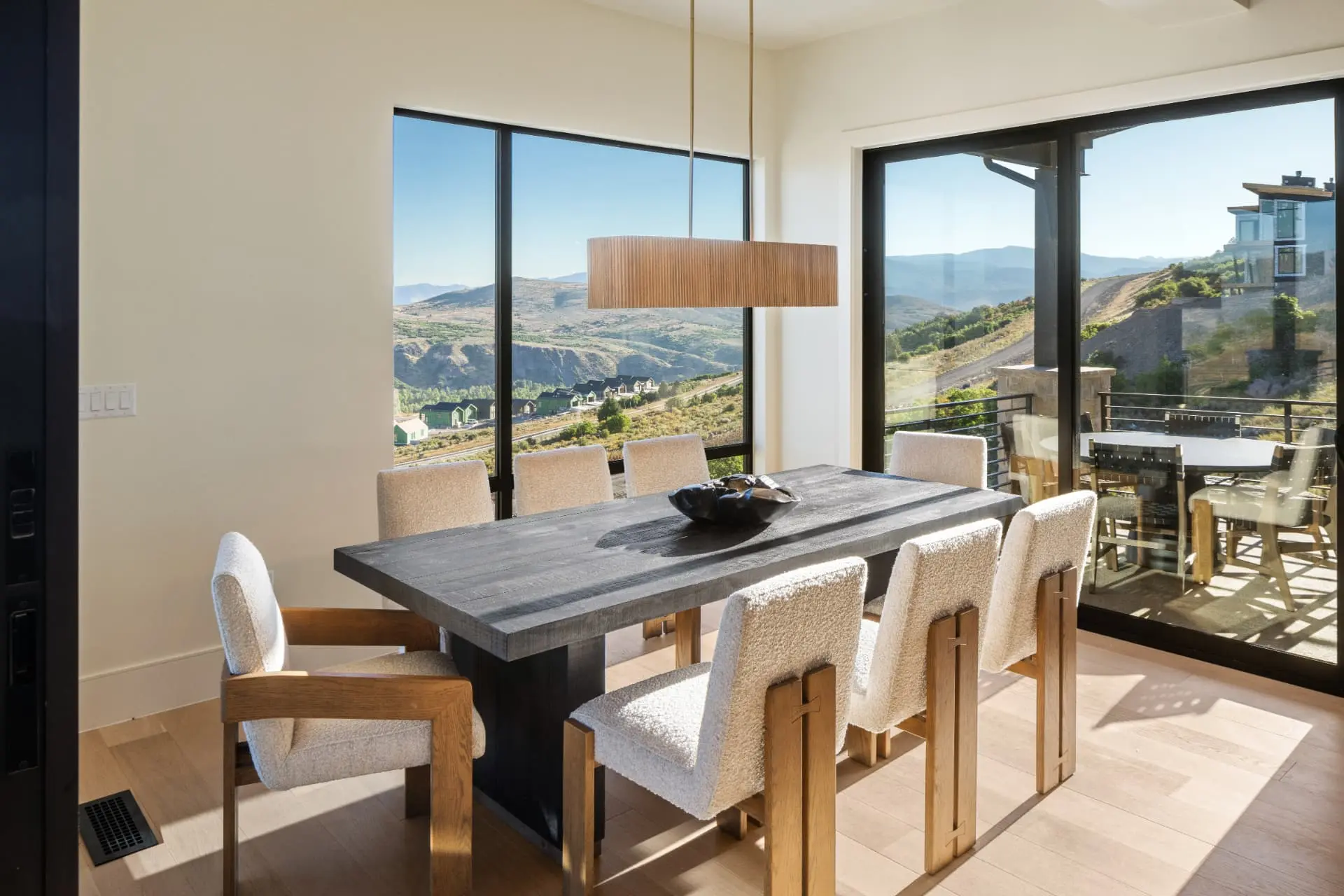 Dining table under a fluted linear pendant with mountain views beyond