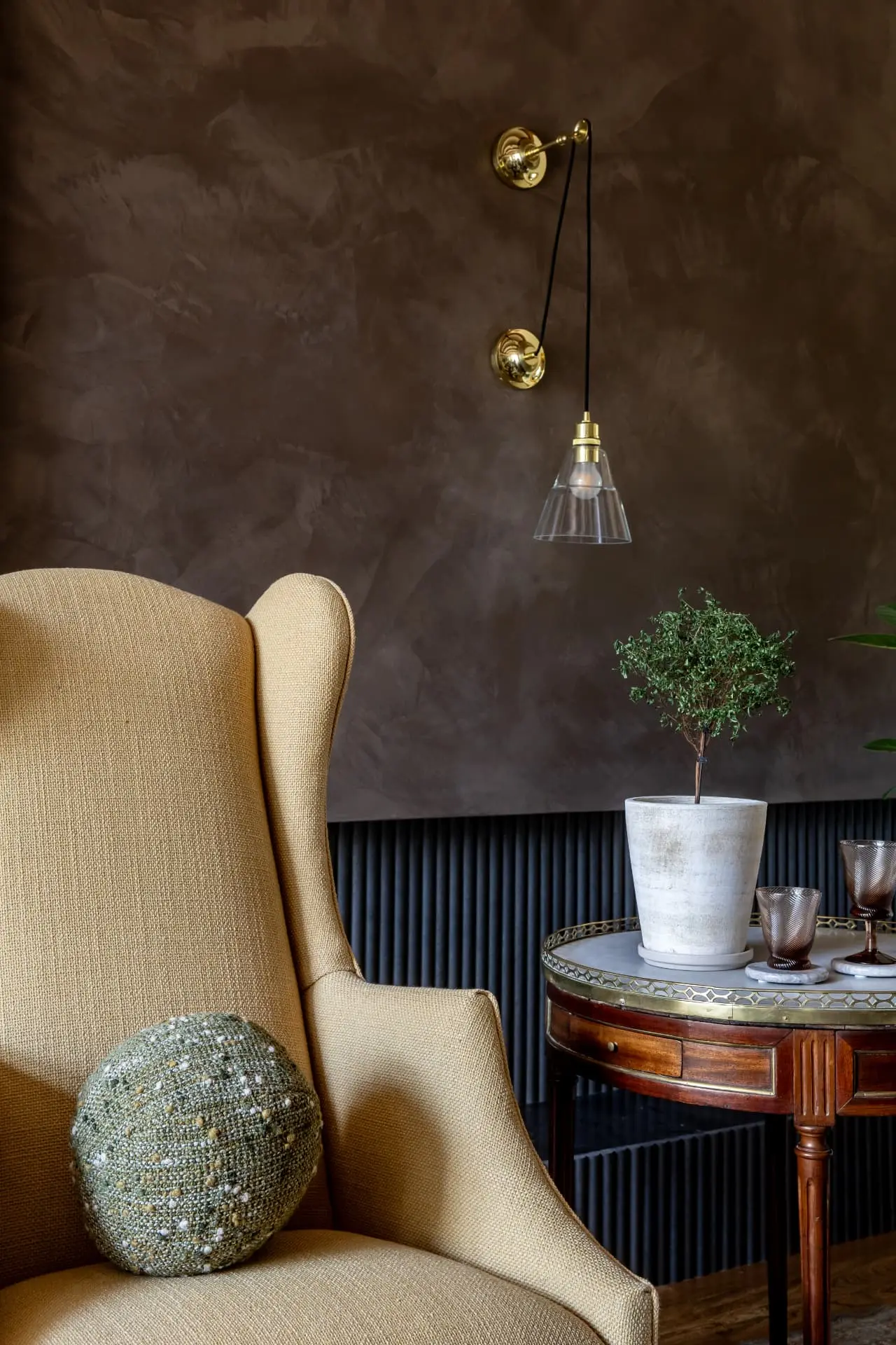 Brass pulley sconce with a clear glass cone shade against a plaster wall