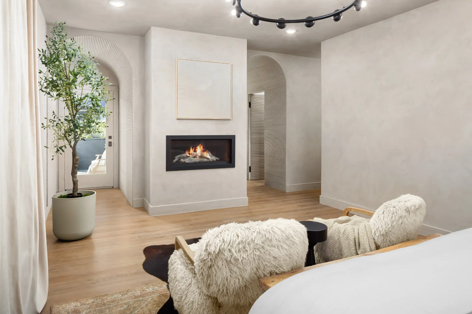Primary suite sitting area with a linear fireplace, arched plaster openings and the orbital ring above