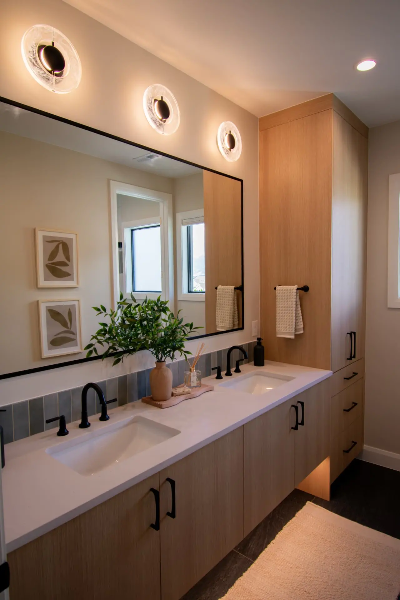 Upstairs double vanity with three alabaster glass disc sconces above a black-framed mirror