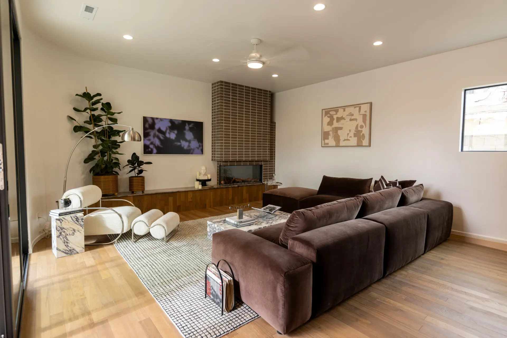 Hearth room with brick fireplace, ceiling fan, and arc floor lamp
