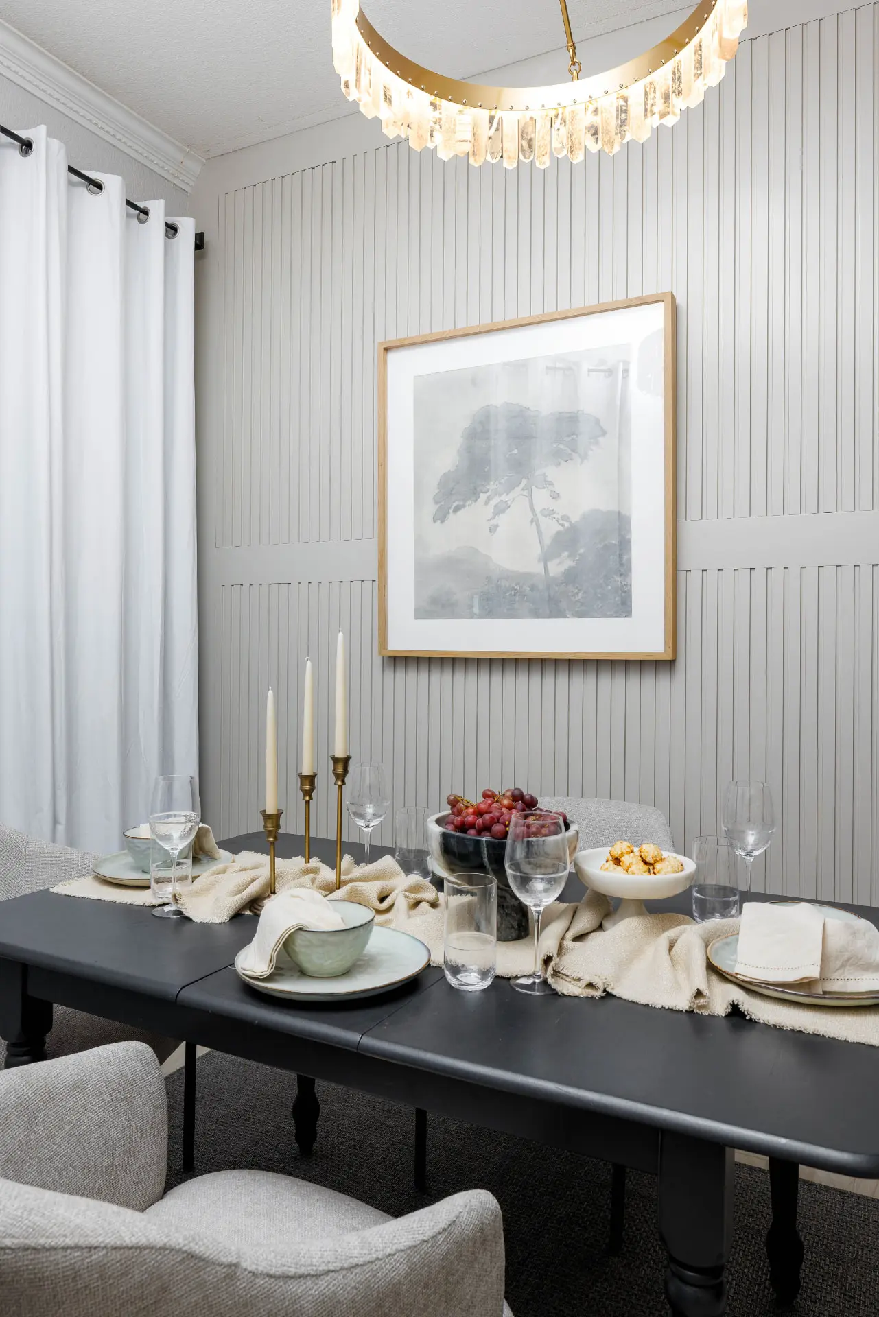 Dining table set beneath the quartz prism chandelier against a fluted paneled wall