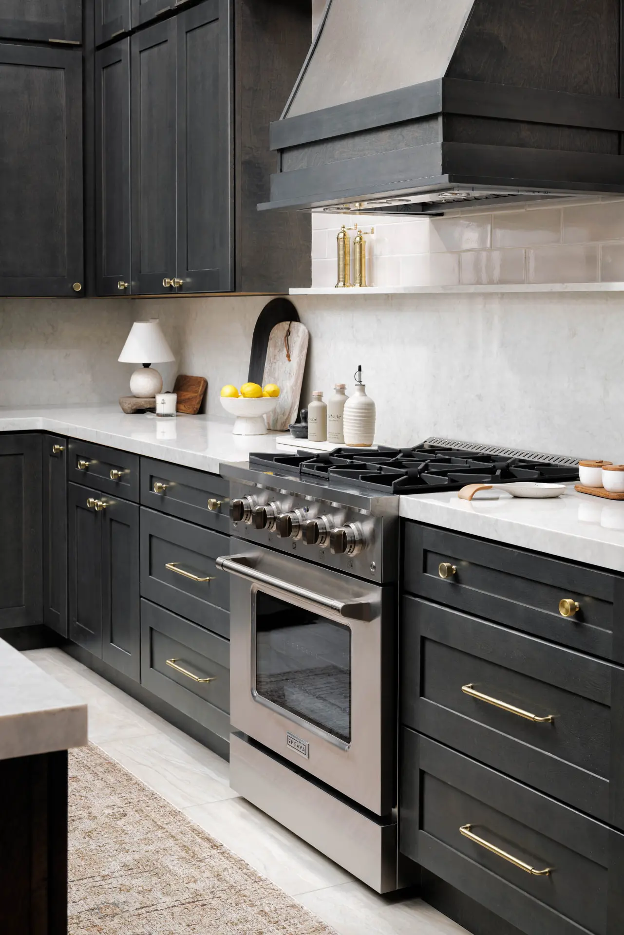 Range wall detail with a wood hood, marble backsplash and brass cabinet hardware