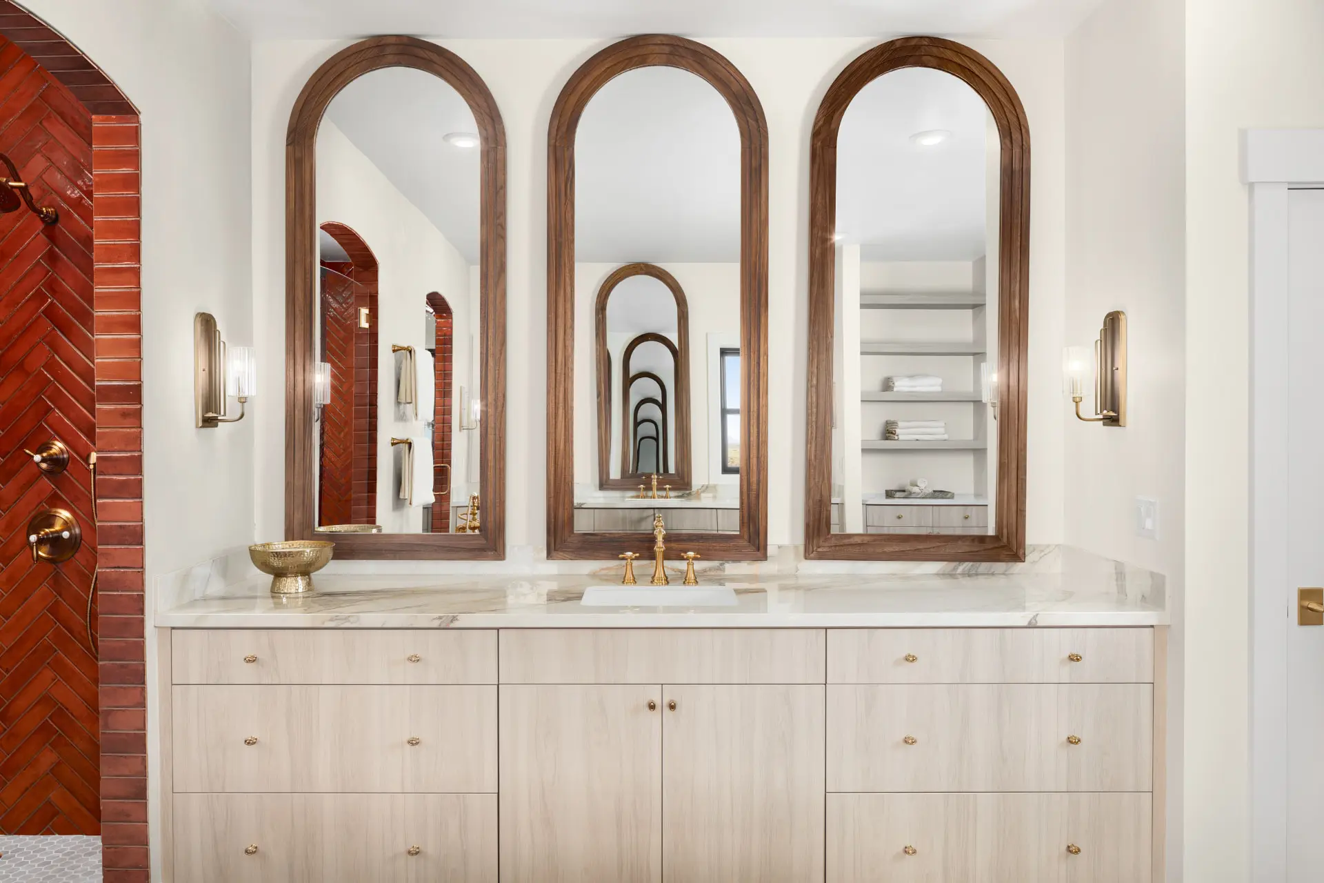 Primary bath vanity with three arched walnut mirrors and reeded glass sconces