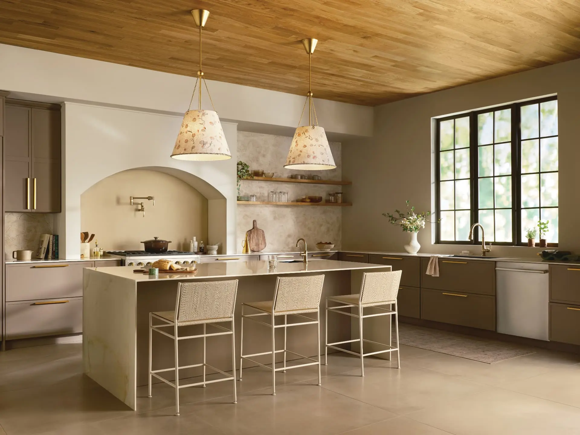 Warm kitchen with wood ceiling, brass pendants and softly patterned shades above a stone island